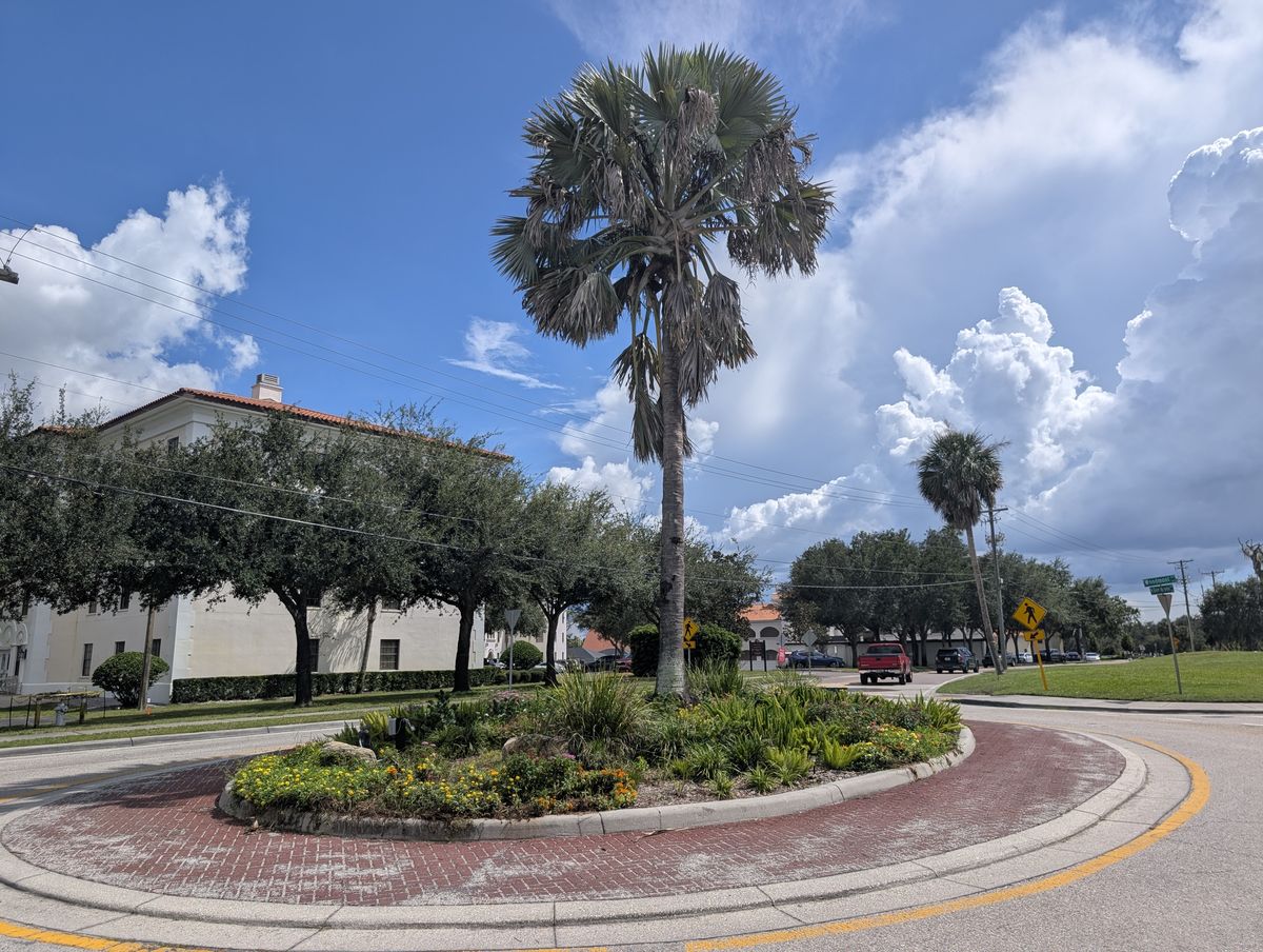 A brick-paved roundabout on the road past Florida College, with a campus building behind it.