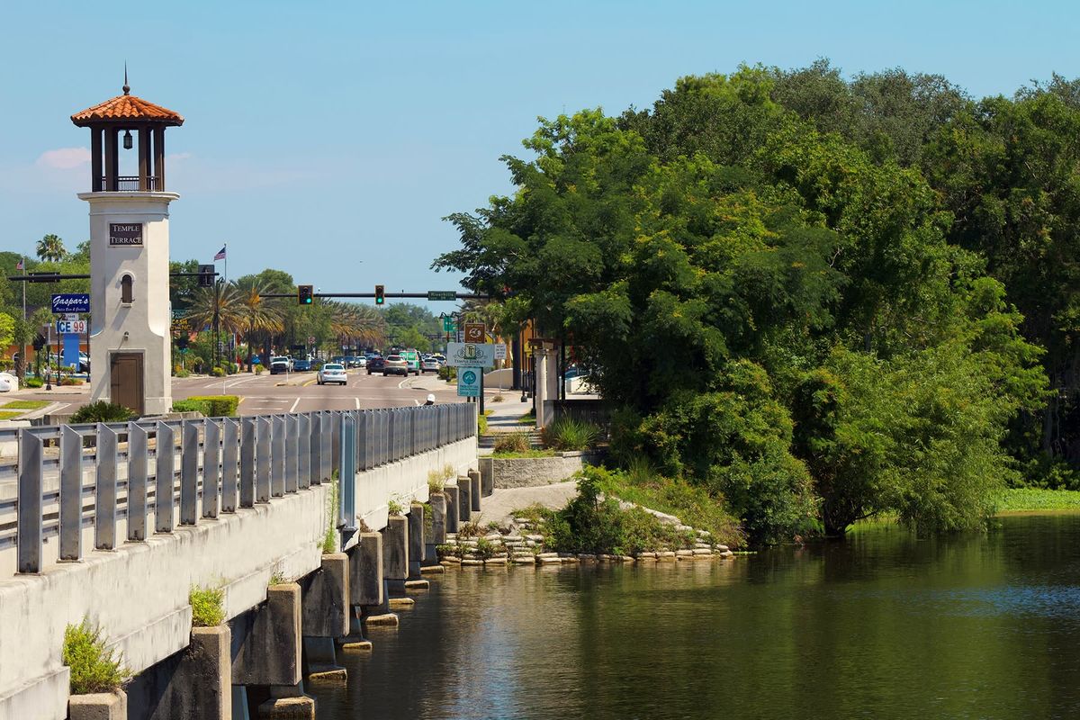 Riverhills Bridge over the Hillsborough River, with the Temple Terrace clock tower and downtown storefronts behind it.