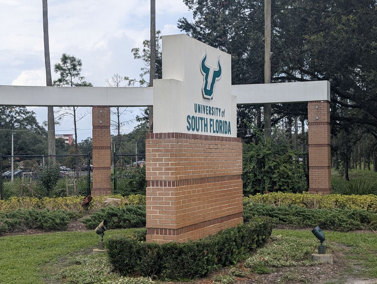 The University of South Florida entrance monument with the Bulls logo, seen from the road.