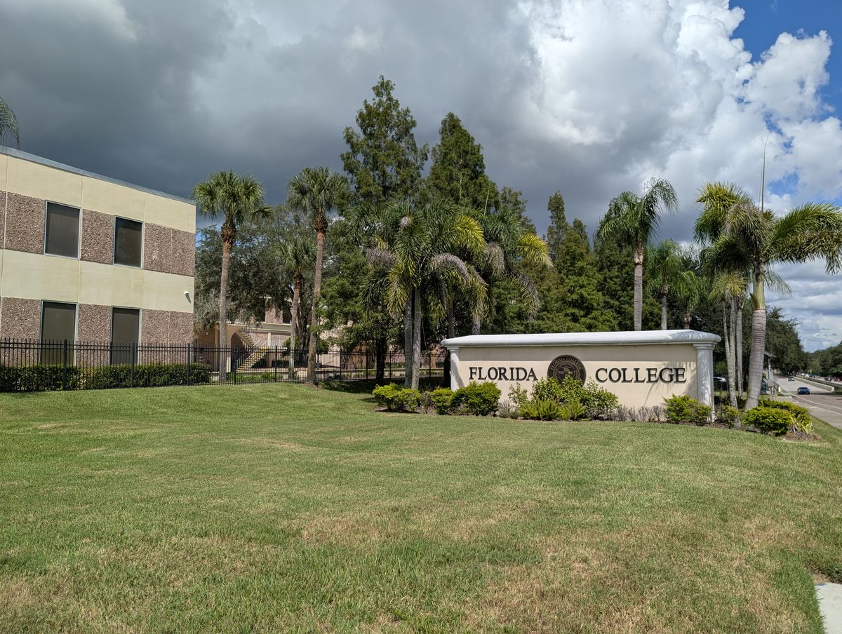 The Florida College frontage in Temple Terrace, seen from the road, with palms and a campus building behind the entrance marker.